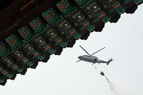 A helicopter drops water as they prepare for the possibility of a wildfire advancing towards Gounsa Temple in Uiseong on 25 March 2025. Deadly wildfires in South Korea worsened overnight as dry, windy weather hampers efforts to contain one of the country's worst-ever fire outbreaks.
