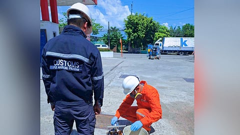 A Customs inspector observes as fuel is transferred into containers for testing during an enforcement operation at a gasoline station in the Bicol Region.