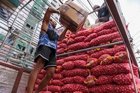 BAGs heavy with harvest, at least 300 kilos of native onions from Northern Luzon are loaded onto a cargo truck in Divisoria, Manila, bound for Naga.