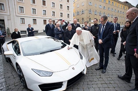 This handout photo taken on November 15, 2017 at the Vatican and released by the Vatican press office, Osservatore Romano shows Pope Francis signing a Lamborghini Huracan received as a gift as Lamborghini CEO Stefano Domenicali (2ndR) looks on.