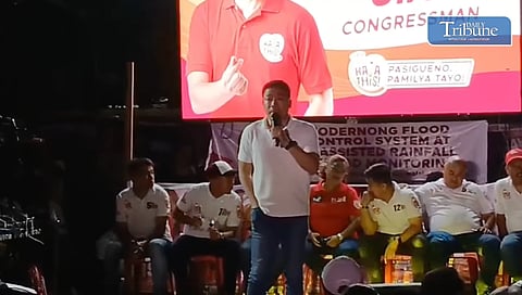 Atty. Christian “Ian” Sia speaks to constituents during a community caucus in Barangay Kapitolyo, Pasig City, as part of Team Kaya This’ campaign sortie. A large campaign poster with his image and slogan is displayed on screen behind him.