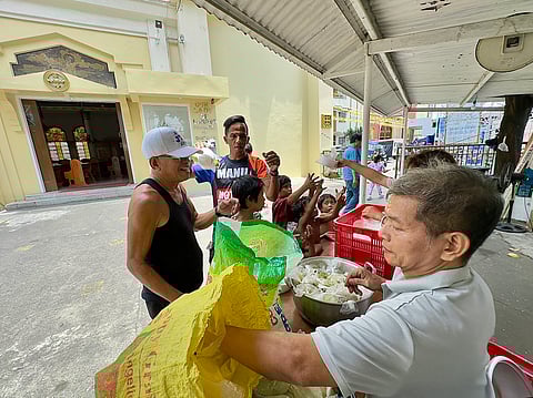 Church volunteers from the National Shrine of Our Lady of Loreto distribute free lunch to community members in Sampaloc, Manila on 3 May 2025.