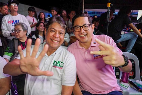Senator-elect Kiko Pangilinan and returning Senator Bam Aquino smile and flash hand signs during a campaign event, surrounded by supporters. Pangilinan wears a white “Para Senador” shirt, while Aquino wears a pink polo bearing his name.