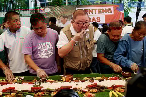 Agriculture Secretary Francisco Tiu Laurel joins a boodle fight-style salu-salo at the DA's Bureau of Animal Industry compound, where participants sample affordable NFA rice from KADIWA centers under the BBM program.