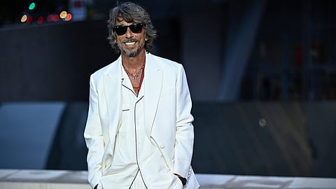 Italian fashion designer Pierpaolo Piccioli smiles in a white suit and sunglasses as he poses on the red carpet at The Fondation Louis Vuitton in Paris on 25 July 2024, ahead of the 2024 Paris Olympics.