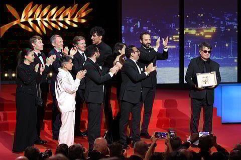 Iranian director and screenwriter and producer Jafar Panahi (R) and his team celebrate on stage after winning the Palme d'Or for the film Un "Un simple accident" (A Simple Accident) during the closing ceremony at the 78th edition of the Cannes Film Festival in Cannes, southern France, on May 24, 2025.