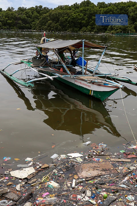 A fisherman wades his boat in a sea of trash at the Bulungan Fishport in Parañaque City on Friday, a day before National Fisherfolks Day. The livelihoods of fisherfolk are at risk not only from the dwindling fish stocks and decline in catch due to overfishing but also from plastic pollution.