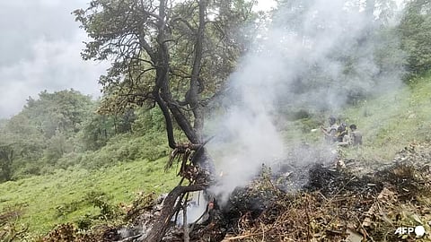 This handout photograph, taken on 15 June 2025, and released by the State Disaster Response Force (SDRF) of India's Uttarakhand state, shows smoke billowing from the site of a chopper crash near Gaurikund. 