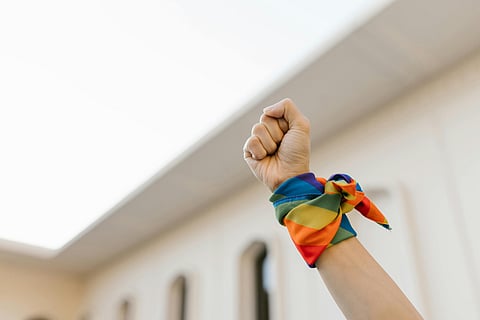 A raised fist adorned with a rainbow bandana symbolizes pride, resistance, and solidarity for LGBTQ+ rights.