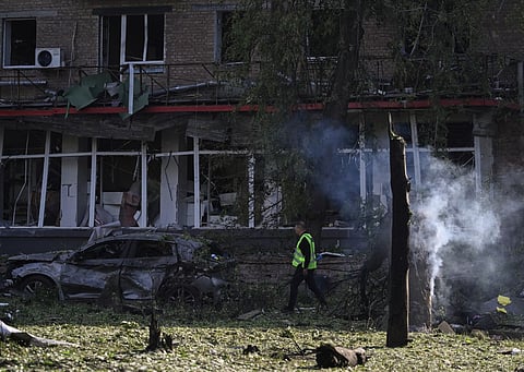 A Police officer walks past a burnt car at the site of a damaged residential building following a Russian missile and drone strike in Kyiv on June 17, 2025, amid the Russian invasion of Ukraine. A Russian attack on Ukraine killed at least 14 people and wounded dozens in the capital, authorities said on June 17, with more wounded reported in the Odesa and Chernigiv regions.
