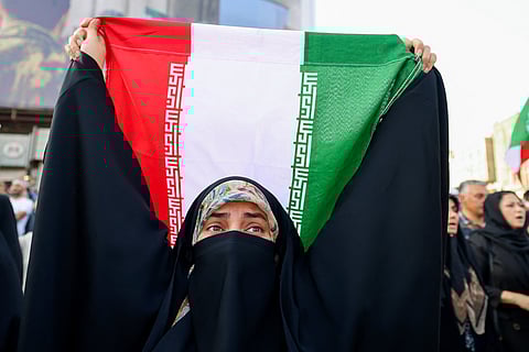 AN Iranian woman lifts a national flag during a rally protesting the US attack on Iran in Enghelab Square in Tehran on June 22, 2025. Iran's President Masoud Pezeshkian condemned US strikes on nuclear sites on June 22, saying in his first response that the attack revealed Washington was "behind" Israel's military campaign in the Islamic republic.