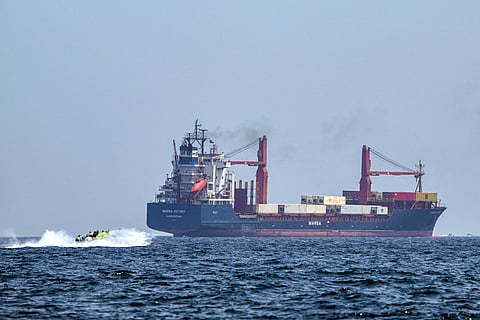 A boat approaches the St Kitt's and Nevis-flagged container ship Marsa Victory while crusing in the waters of the Strait of Hormuz off the coast of Khasab in Oman’s northern Musandam peninsula on June 25, 2025.
