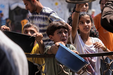 Children queue with pots to receive meals from a charity kitchen in Gaza City on July 14, 2025. With the war in Gaza now in its 22nd month and Israel only slightly easing an aid blockade of the Palestinian territory, shortages of everything from food to clean water have hit everyone.
