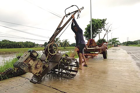 Two young farmers detach the kuliglig from a trailer after using it as a means of transportation, and is being fitted with tillers to aerate the soil in a rice farm in Morong, Bataan. 