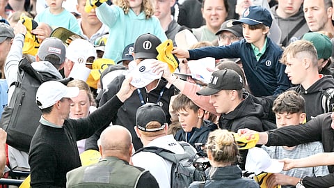 Northern Ireland’s Rory McIlroy (left) signs autographs for fans beside the 18th green after a practice round ahead of the 153rd Open Championship at Royal Portrush golf club in Northern Ireland on Tuesday.