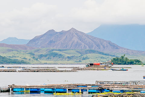 TAAL Volcano looms in the background as the Philippine Coast Guard conducts search and recovery operations off Laurel, Batangas — where the remains of the missing sabungeros were allegedly dumped. A tarped banca and an ROV assist divers facing poor visibility and harsh underwater conditions.