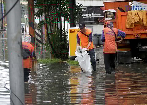 Department of Public Works and Highways (DPWH) personnel collect garbage washed up by floodwaters along Araneta Avenue in Quezon City on Saturday, 19 July 2025, following heavy rainfall. 