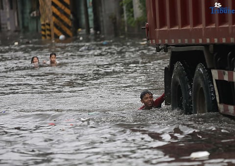 Children bathe and play in waist-deep floodwaters along Maria Clara Street in Quezon City on Saturday, 19 July 2025, following continuous rains from the Habagat, intensified by Severe Tropical Storm Crising.