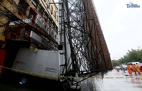 Bureau of Fire Protection personnel prepare to remove a collapsed billboard along the southbound lane of Katipunan Avenue in Quezon City on Saturday, July 19, 2025. The structure was toppled by strong winds around 11 a.m., brought by the Habagat intensified by Severe Tropical Storm Crising. Two vehicles reportedly crashed in the incident.