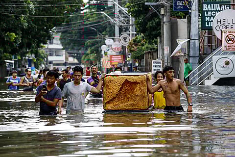 RESIDENTS wade in waist-level flood inside the Vista Verde Subdivision in Cainta, Rizal.