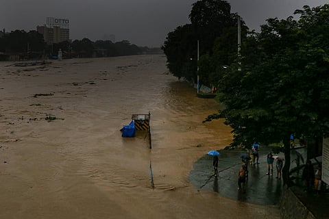 Residents monitor the water level of the Marikina River as it hits the second alarm at 3:00 in the afternoon of 21 July 2025 due to heavy rains brought by Habagat.