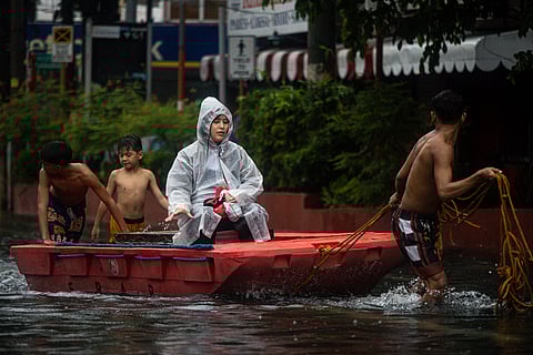 People wade through the flooded roads along España Avenue in Manila on Tuesday, 22 July 2025, as the southwest monsoon or habagat continue to bring persistent rains in the region.