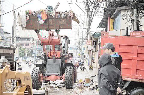 Workers from the local government of Valenzuela conduct clearing and cleaning operations in the city amid the flooding due to the storms and the southwest monsoon.