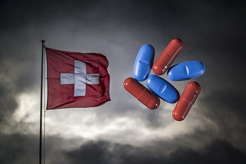 This illustration photograph shows tablet and capsule medicines by Swiss pharmaceutical Sandoz on a picutre of a Swiss flag, in Lausanne on August 1, 2025, as Washington said it planned to charge a 39 percent tariff rate on Swiss goods. The Swiss government said on August 1, 2025 it would negotiate with the United States to try to avoid the 39 percent punitive US tariff rate that would ravage its key pharmaceutical industry.