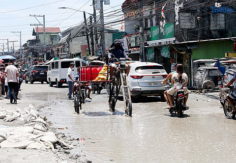 An improvised motorbike designed to navigate floods hauls water containers along a submerged portion of Apalit-Macabebe Road in Pampanga on Monday, July 4. Pampanga remains among the provinces most vulnerable to flooding.
