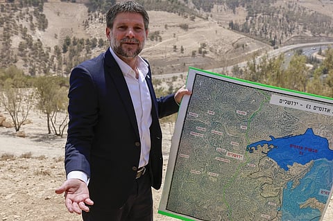 Israeli far-right Finance Minister Bezalel Smotrich holds a map of an area near the settlement of Maale Adumim, a land corridor known as E1, outside Jerusalem in the occupied West Bank, on August 14, 2025, after a press conference at the site. Israel's finance minister on August 14 backed plans to build 3,400 homes in a contentious area of the occupied West Bank, calling for the territory's annexation in response to several countries announcing plans to recognise a Palestinian state.
