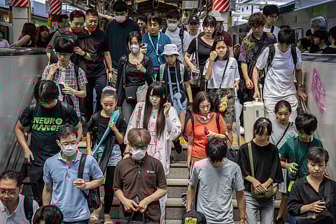 People walk down the stairs after disemberking from a train at Shinjuku station in Tokyo on August 14, 2025.



