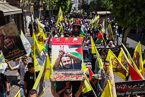 Protesters lift flags and placards depicting leading member of the Fatah party Marwan Barghouti, the most high-profile Palestinian detainee in Israeli custody, during a march supporting him in Ramallah city in the occupied West Bank on August 19, 2025. The UN's human rights office on Ausust 19 condemned Israel's far-right national security minister Itamar Ben Gvir for taunting Barghouti, who has spent more than 20 years behind bars after being sentenced for his role in anti-Israeli attacks in the early 2000s, and sharing the footage online.

