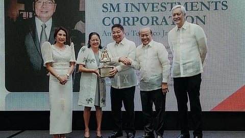 AMANDO Tetangco Jr., chairman of the board of SM Investments (center), receives the Grand Tourism Excellence Award from the Manila Overseas Press Club at New World Makati on 15 August. Joining him on stage are (from left) Tourism Secretary Christina Garcia Frasco, First Lady Louise Araneta-Marcos, and MOPC officials Tony Lopez (chairman) and Eric Canoy (president).