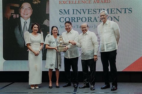 AMANDO Tetangco Jr., chairman of the board of SM Investments (center), receives the Grand Tourism Excellence Award from the Manila Overseas Press Club at New World Makati on 15 August. Joining him on stage are (from left) Tourism Secretary Christina Garcia Frasco, First Lady Liza Araneta-Marcos, and MOPC officials Tony Lopez (chairman) and Eric Canoy (president).