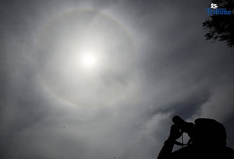 A photographer captures a visible sun halo in Quezon City on Monday. The atmospheric phenomenon occurs when sunlight refracts and reflects off tiny ice crystals suspended in high-altitude cirrus clouds.