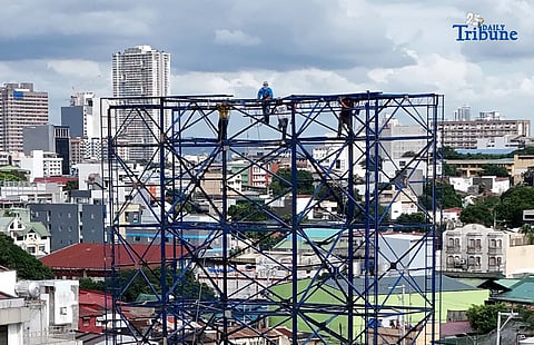 Workers were seen atop a construction billboard along EDSA in Quezon City on Thursday. On the same day, a Senate lawmaker presided over the first organizational meeting and public hearing of the Committee on Labor, Employment and Human Resource Development, which tackled proposed measures on minimum wage increases.