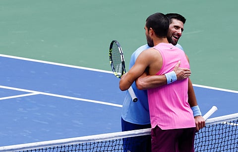 Spain's Carlos Alcaraz (R) and Serbia's Novak Djokovic (L) hug at the net after Alcaraz victory in their men's singles semifinal tennis match on day thirteen of the US Open tennis tournament at the USTA Billie Jean King National Tennis Center in New York City, on September 5, 2025.