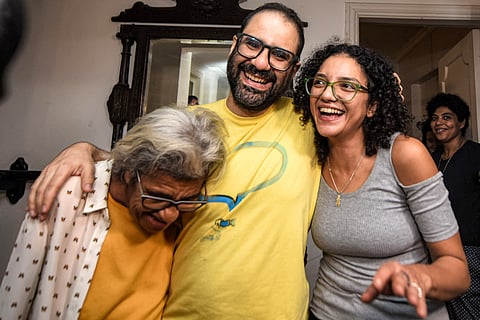 British-Egyptian activist Alaa Abdel Fattah (center) embraces his mother, writer Laila Soueif (left), and his sister Sanaa Seif (right), at home after his release in Cairo on 23 September 2025 prompting an emotional reunion with his loved ones after a pardon from President Abdel Fattah al-Sisi.