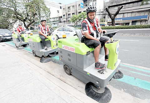 SANITATION workers use sweeping machines to clean bike lanes along Kalayaan Avenue, Quezon City. A garbage collector (below, left) puts trash in a compactor.