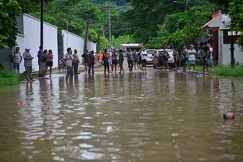 People stand on a flooded street following heavy rains in Poza Rica, Veracruz state, Mexico, on October 10, 2025. The heavy rains that occurred on October 9, 2025, in Mexico caused two deaths, as well as flooded homes, landslides, and overflowing rivers in various parts of the country, the Mexican government reported on Friday.
