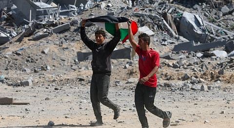 Two Palestinian youth react to the news of the ceasefire between Israel and Hamas from Khan Younis. Photo by Ramadan Abed on Reuters.