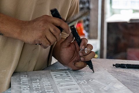 Tombstone maker Socsoc Gamurot engraves and paints names on a marble slab at his makeshift workshop inside the Manila North Cemetery as the annual observance of All Saints’ Day approaches.

 he 40-year-old, who resides inside the country’s largest cemetery, shares that each tombstone costs ₱1,200 and that he crafts an average of 10 pieces a day.
