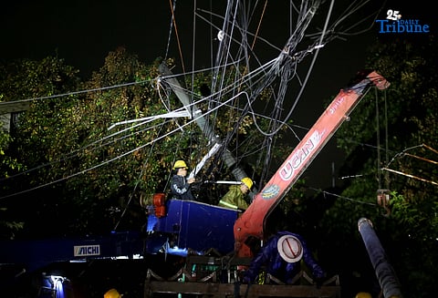 ELCOR, a Meralco contractor, responds to a toppled electric post along K-1st Street in Quezon City early Monday, after strong winds from Super Typhoon Uwan caused a tree to fall and damage the line.