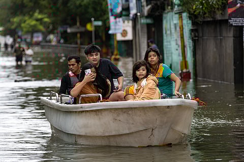 People wade through chest-deep floodwater in Barangay Navotas East, Navotas City on Monday, 10 November 2025, after the Malabon-Navotas Navigational Gate overflowed Sunday night amid high tide and storm surges driven by Super Typhoon Uwan.