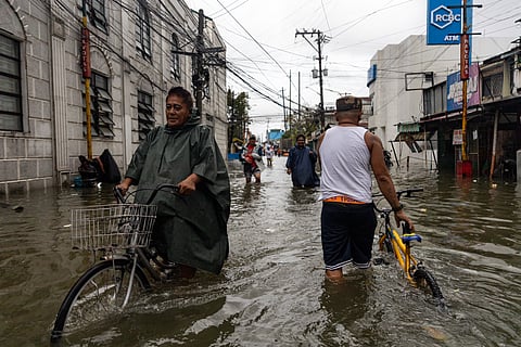 People wade through chest-deep floodwater in Barangay Navotas East, Navotas City on Monday, 10 November 2025, after the Malabon-Navotas Navigational Gate overflowed Sunday night amid high tide and storm surges driven by Super Typhoon Uwan.
