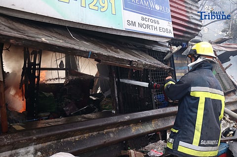 Firefighters work to extinguish a third-alarm blaze that tore through a residential area and a junk shop along Mindanao Avenue in Barangay Bagong Pag-asa, Quezon City on Tuesday. The fire was declared out at 8:28 a.m., leaving at least 85 families displaced.