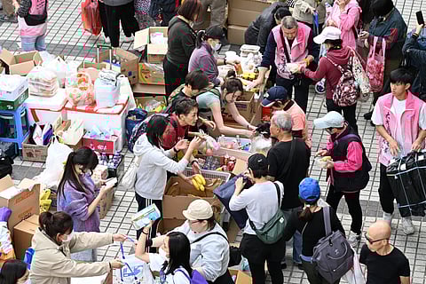 Smoldering Firefighters regroup at Wang Fuk Court in Hong Kong’s Tai Po district on Thursday as a towering inferno turns apartment blocks into charred husks, killing at least 55 and leaving hundreds unaccounted for. Inset: Volunteers hand out food and drinks to survivors and exhausted responders amid the chaos.
