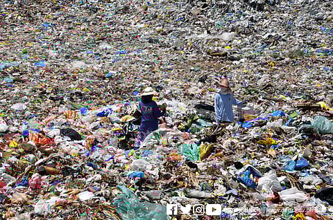 Two workers stand in a landfill.