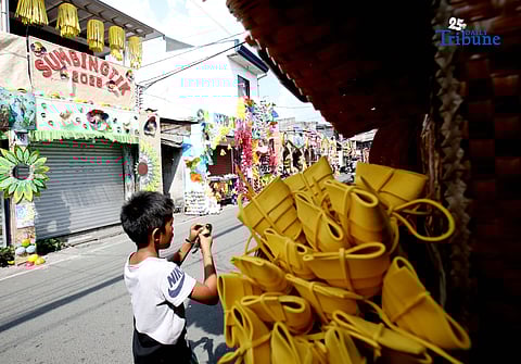 (December 01 2025) Pedestrians walk past houses decorated with colourful reusable materials as part of the 2025 SumBingTik (Suman, Bibingka, Latik) Festival in Cainta, Rizal on Monday December 1 2025. The SumBingTik Festival is an annual cultural long-week festival held in Cainta, Rizal, along with the town's founding anniversary and the feast of Our Lady of Light which is celebrated on December 1, the patron saint of the town. The festival was first celebrated in 2014. Photo/Analy Labor