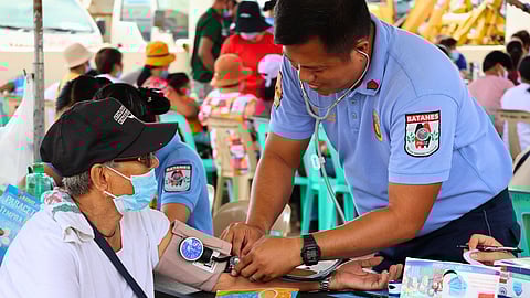 A senior citizen resident of Ivana, Batanes Province, having her vital signs checked with a local volunteer police officer, before her consultation with a doctor.